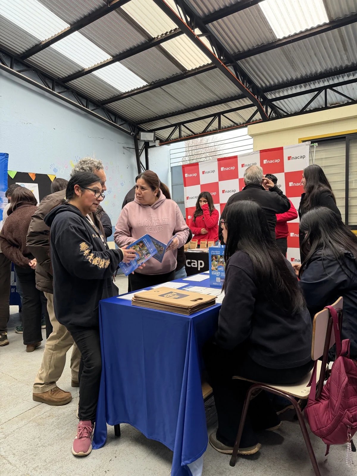 Participantes conversan y revisan material informativo en el espacio de INACAP.